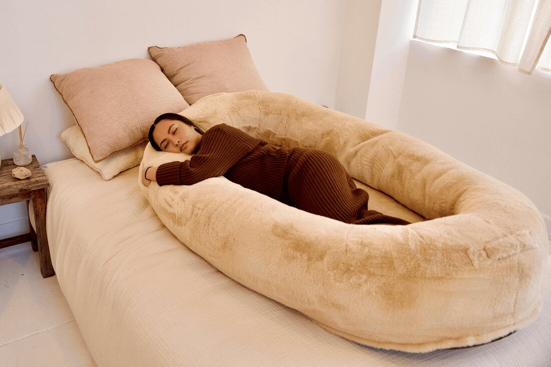 A photo of a Plufl Dog Bed for Humans. The bed is a large, plush bed made with soft, faux fur and has 360-degree bolsters for support. It is perfect for people who want to relax and de-stress